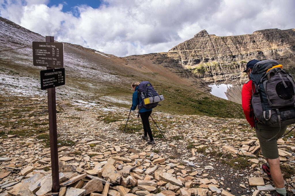 Backpacker mit großem Rucksack blickt auf eine Berglandschaft