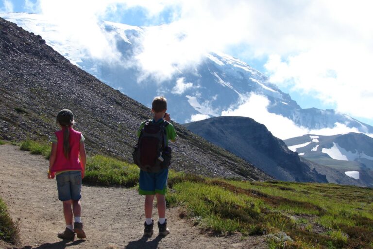 Zwei Kinder mit Rucksäcken auf einem Wanderweg in den Bergen