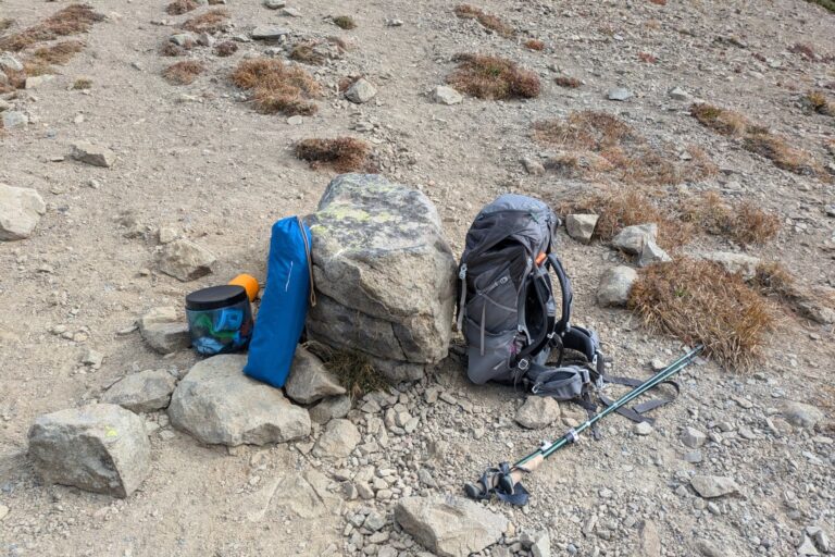 Trekkingrucksack mit Stöcken, Zelt und Isomatte auf felsigem Untergrund